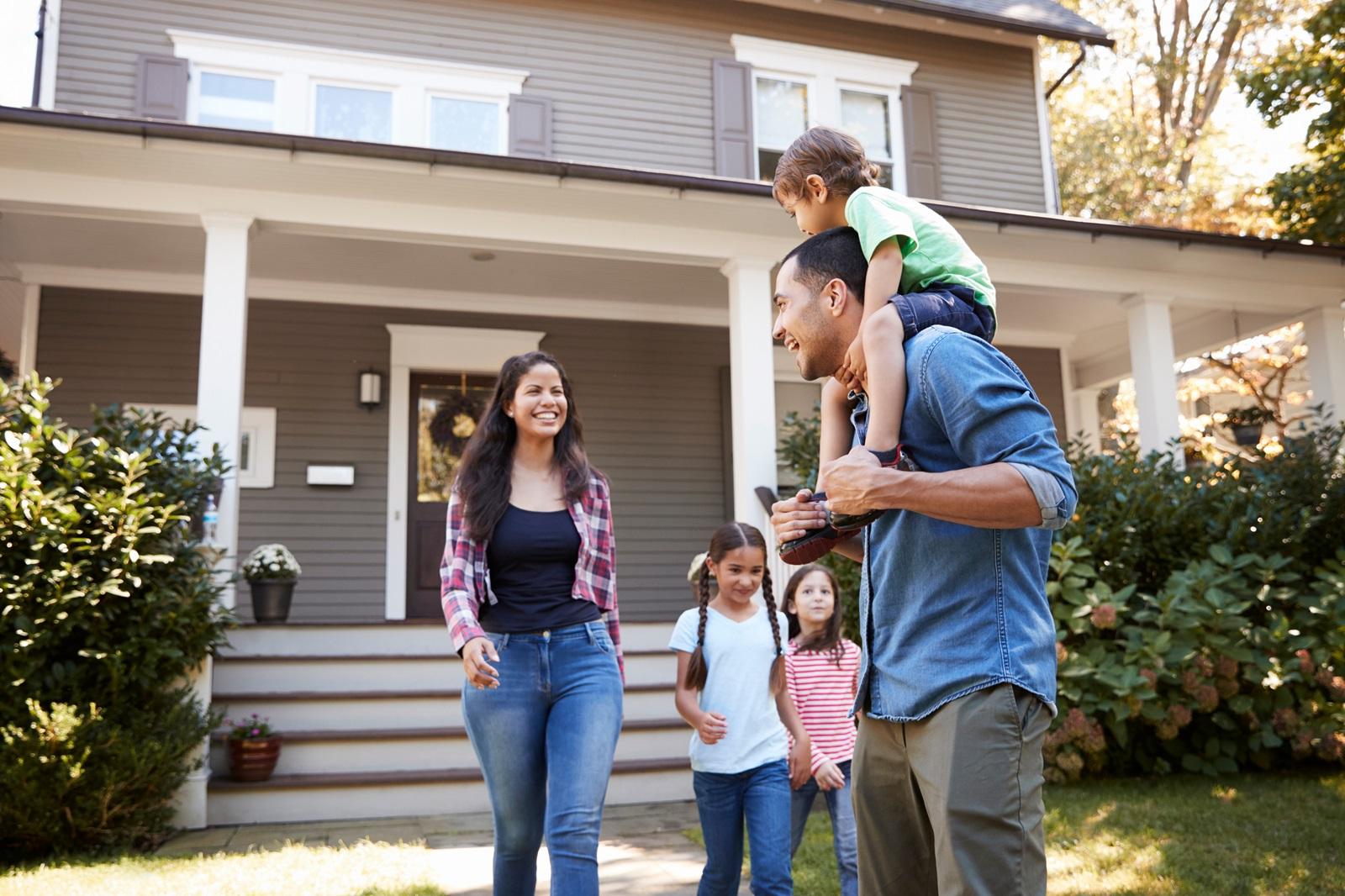 A young couple with three children walk down the sidewalk of their new home.